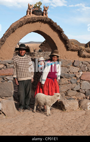 Le mouton domestique (Ovis ammon f. bélier), Quechua family standing dans une arche à leur maison en pierre, le Pérou, l'Atuncolla Banque D'Images