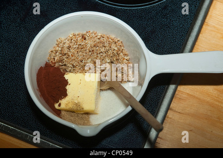 Le noisetier commun (Corylus avellana), l'auto-prélevés et les noisettes moulues, la poudre de cacao, le beurre et le sucre dans une casserole sur la cuisinière pour faire le chocolat se propager, Allemagne Banque D'Images