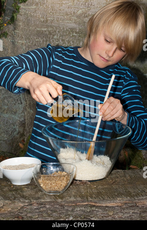 Boy making pesto de noix auto-prélevés et les graines de tournesol, l'huile d'olive est ajouté, Allemagne Banque D'Images