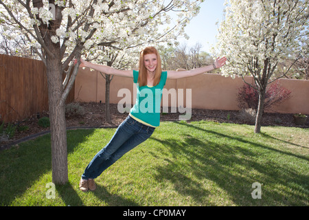Quinze ans, fille Holding on to a blossoming pear tree en arrière-cour. Banque D'Images