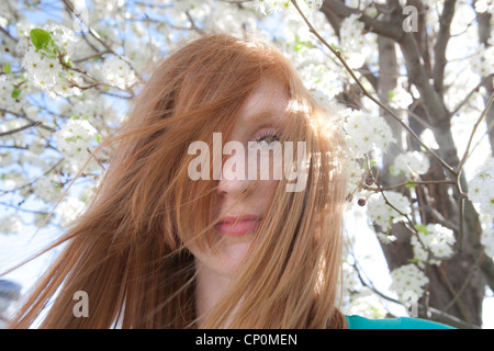 Quinze ans, fille de rouge les cheveux au vent à la recherche à l'appareil photo. Banque D'Images