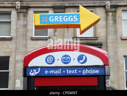 Signer, au-dessus de cabine téléphonique, pointant vers le Greggs bakers Newcastle Upon Tyne, England, UK Banque D'Images