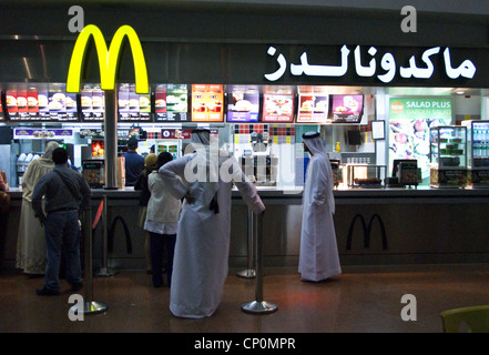 Les hommes en robe arabe traditionnelle au MCDONALD'S, l'aéroport international de Dubai, Dubaï, Émirats Arabes Unis Banque D'Images