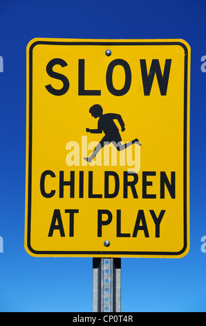 Les enfants lents à jouer street sign avec fond de ciel bleu Banque D'Images