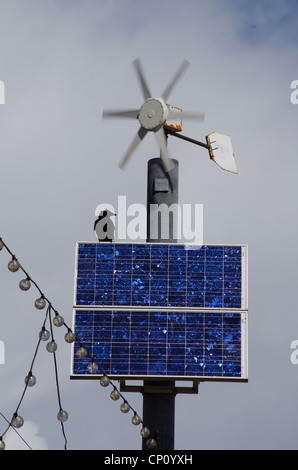 Un corbeau heureusement assis sous une éolienne, perché sur panneau solaire, Paignton, Devon pouvoirs d'énergie renouvelable la pendaison lumières. Banque D'Images