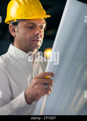 Homme d'âge moyen travaillant comme architecte et plan de construction de lecture in office Banque D'Images