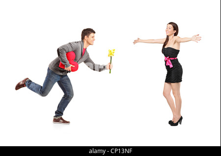 Jeune homme en marche avec un bouquet de fleurs et coeur rouge objet forme et excité femme isolé sur fond blanc Banque D'Images