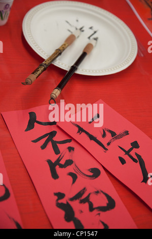 Calligraphie chinoise fraîchement rédigé à l'aide de l'encre noire et des pinceaux en bambou sur papier rouge. Banque D'Images