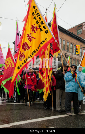 Les participants du défilé du Nouvel An chinois 2012 drapeaux portent dans les rues de Vancouver's China Town. Banque D'Images