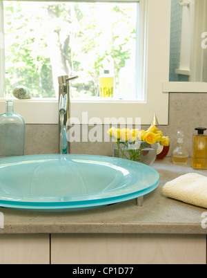 Lavabo en verre bleu situé sur l'unité recouvert de marbre dans la salle de bains contemporaine Banque D'Images