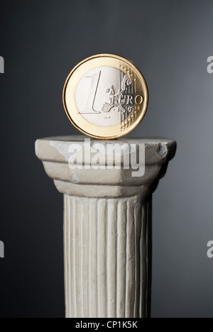 € coin se tient sur une colonne classique devant un arrière-plan sombre. Banque D'Images