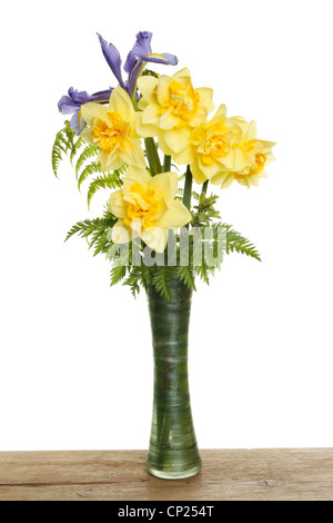 Bouquet de jonquilles avec un iris bleu et vert de fleurs dans un vase sur une planche en bois Banque D'Images