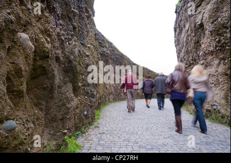 Les visiteurs de marcher sur l'allée pavée bordée de murs earthern, menant à l'entrée du monastère de Varlaam, région des météores, Grèce. Banque D'Images