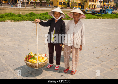 Deux femmes vietnamiennes, l'un portant des fruits, Hoi An, Quang Nam Province, Vietnam Banque D'Images