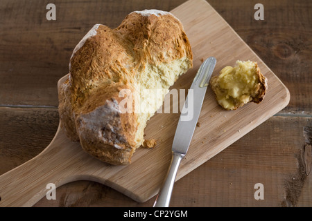 Une miche de pain maison fraîchement cuits et chauds du four et servi avec du beurre. Banque D'Images