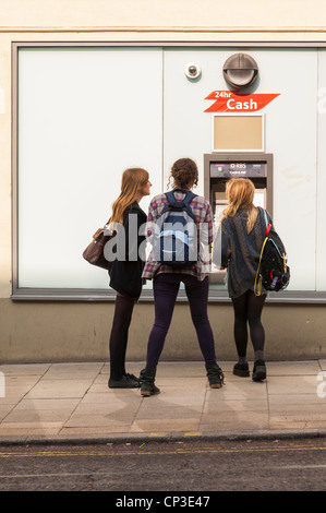 Trois filles le retrait d'argent d'un distributeur de billets 24h à Norwich , Norfolk , Angleterre , Angleterre , Royaume-Uni Banque D'Images