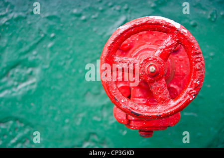 Une valve de roue rouge sur un métal vert Banque D'Images