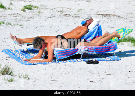 Couple relaxing on beach. Femme lisant, l'homme de veille Banque D'Images