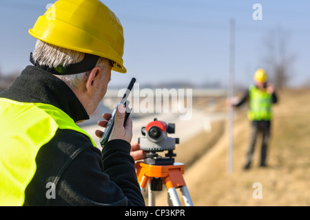 Les géomètres mesure avec tachéomètre parlant à travers la route de l'émetteur Banque D'Images
