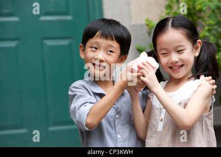 Jeune chinois garçon et fille avec piggy bank Banque D'Images