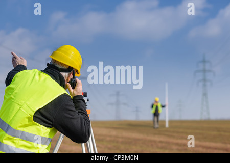 Les géomètres mesure avec tachéomètre parlant à travers le site de construction de l'émetteur Banque D'Images