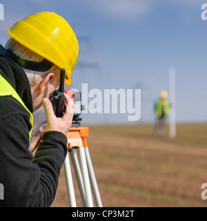 Les géomètres la mesure de terre avec tachéomètre parlant à travers émetteur Banque D'Images