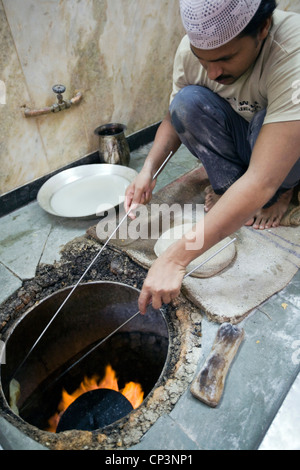 L M Rahman la préparation et la cuisson du pain naan frais dans le four tandoor à Karim's Restaurant, Delhi, Inde Banque D'Images