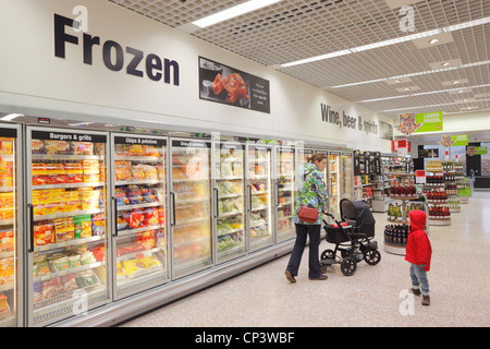 Femme poussant un landau avec fils courses dans un supermarché de l'allée des surgelés. Banque D'Images