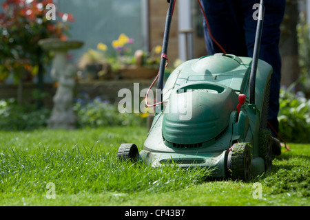 Tondre la pelouse jardinier en avril. Couper le gazon. Travaux de jardinage Banque D'Images