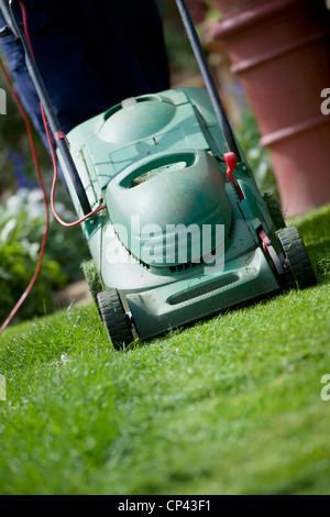 Tondre la pelouse jardinier en avril. Couper le gazon. Travaux de jardinage Banque D'Images