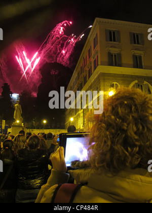 Femme à l'aide d'ipad pour photographie d'artifice sur la Piazza del popolo à Rome Italie Banque D'Images