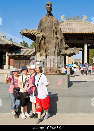 Un groupe de Chinois les femmes qui posent pour une photo à côté d'une statue à l'entrée de la nouvelle construction à Grottes de Yungang. Banque D'Images