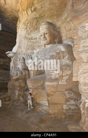 Un touriste à l'intérieur du Lin Yan Cave (grotte n°3) qui pose pour une photo à côté de la bodhisattva au Grottes de Yungang. Banque D'Images