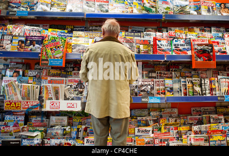 Vue arrière d'un homme debout et lire des magazines dans une succursale de W H Smith marchands, UK Banque D'Images