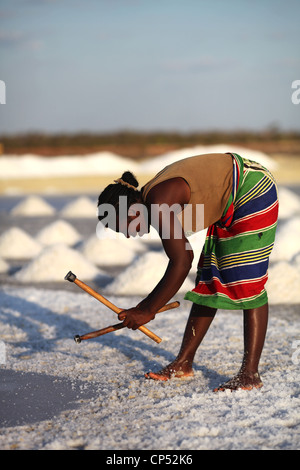 Une femme malgache dans une jupe colorée, casser la croûte de sel au milieu du champs de sel près de Belo sur Mer Banque D'Images