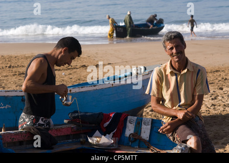 Faire du thé les pêcheurs dans leurs barques sur la plage à Taghazout Banque D'Images