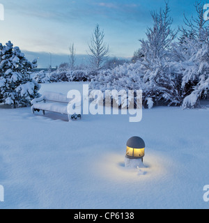 Banc couvert de neige et la lumière des arbres dans un parc près de Reykjavik, Islande Banque D'Images