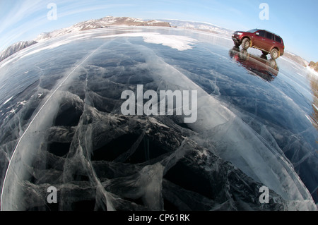 Voiture rouge sont à l'origine le long de la glace d'un lac gelé. Le lac Baïkal, l'île Olkhon, Sibérie, Russie Banque D'Images