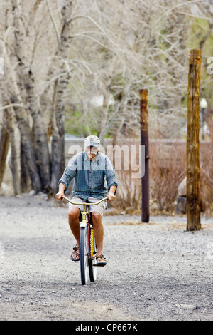 Cycliste solitaire se déplace sur le terrain de l'autre côté de la rivière Arkansas du centre-ville de Salida, Colorado. Banque D'Images