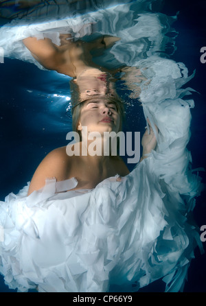 Une jeune femme avec de grands cheveux de poser dans un pool underwater Banque D'Images
