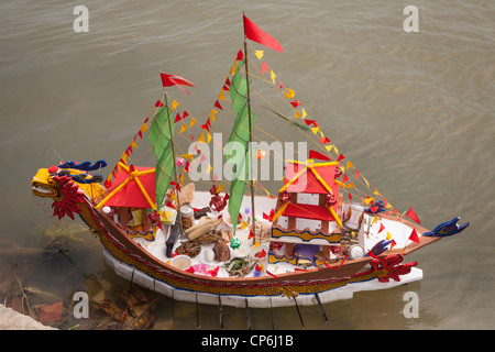 Une réplique modèle réduit bateau chargé de offrandes religieuses à la Déesse de la mer, sur la rivière Thu Bon, Hoi An, Vietnam Banque D'Images