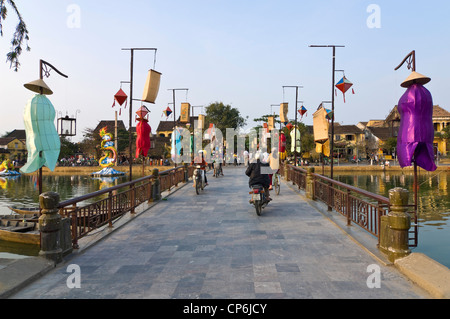Vue horizontale de cyclomoteurs, motos et vélos traversant le pont de la rivière Thu Bon décorées dans Hoi An, ville ancienne. Banque D'Images