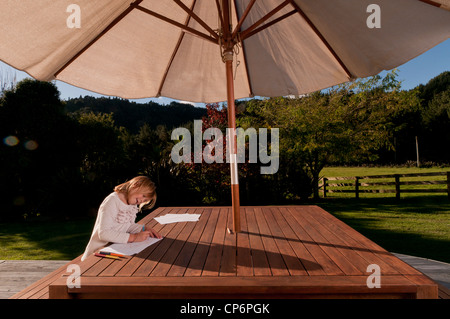 Girl sur woodne table sous Parasol, Nouvelle-Zélande Banque D'Images