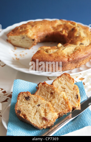 Tranches de pomme et les raisins secs gâteau dans une petite plaque avec le gâteau légèrement blurried dans l'arrière-plan Banque D'Images