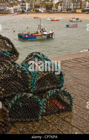 Des casiers à homard sur Smeaton's Pier, St Ives, Cornwall, avec des bateaux de pêche dans le port au-delà. Banque D'Images