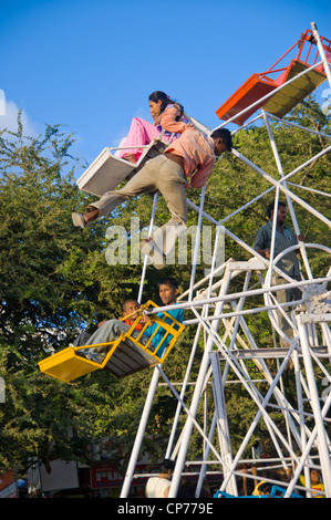 Pouvoirs d'un homme d'une grande roue sans moteur par grimper au sommet, suspendu sur le bord et le saut vers le bas tout en maintenant l'Inde Bombay. Banque D'Images