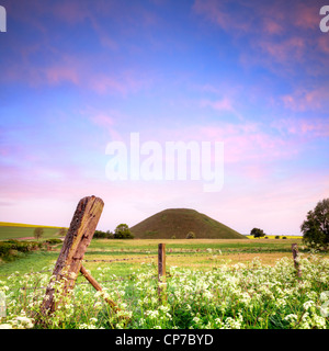 Silbury Hill, un monument néolithique dans le Wiltshire, nearAvebury, sur un beau matin de printemps avec ciel bleu et nuages roses. Banque D'Images