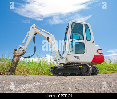 Petit tracteur Caterpillar se dresse sur l'asphalte contre le ciel bleu Banque D'Images