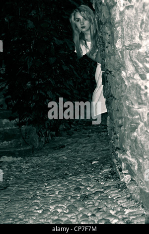 Jeune femme regarde nuit dans une ruelle sombre au coin de la Banque D'Images