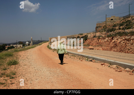 Une femme palestinienne marche à travers le site de construction de la barrière de séparation israélienne construite dans le village d'al-Walaja en Cisjordanie Banque D'Images